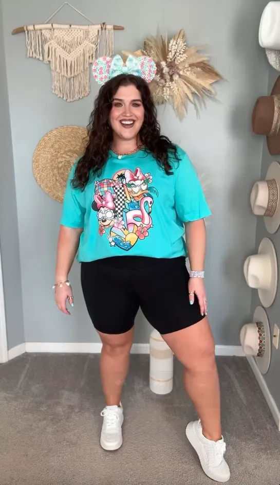 Casual plus size summer theme park outfit for moms with turquoise graphic tee, black bike shorts, and Minnie ears