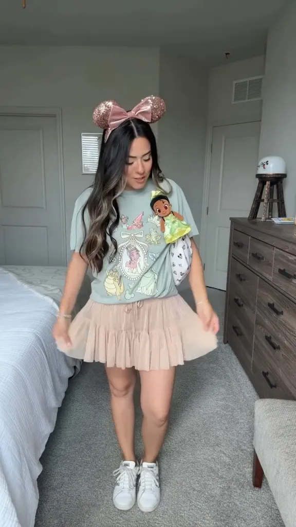Mom in pink Minnie ears, sage green Disney princess tee, and blush pink tiered tulle skirt—whimsical summer Disney outfit idea.
