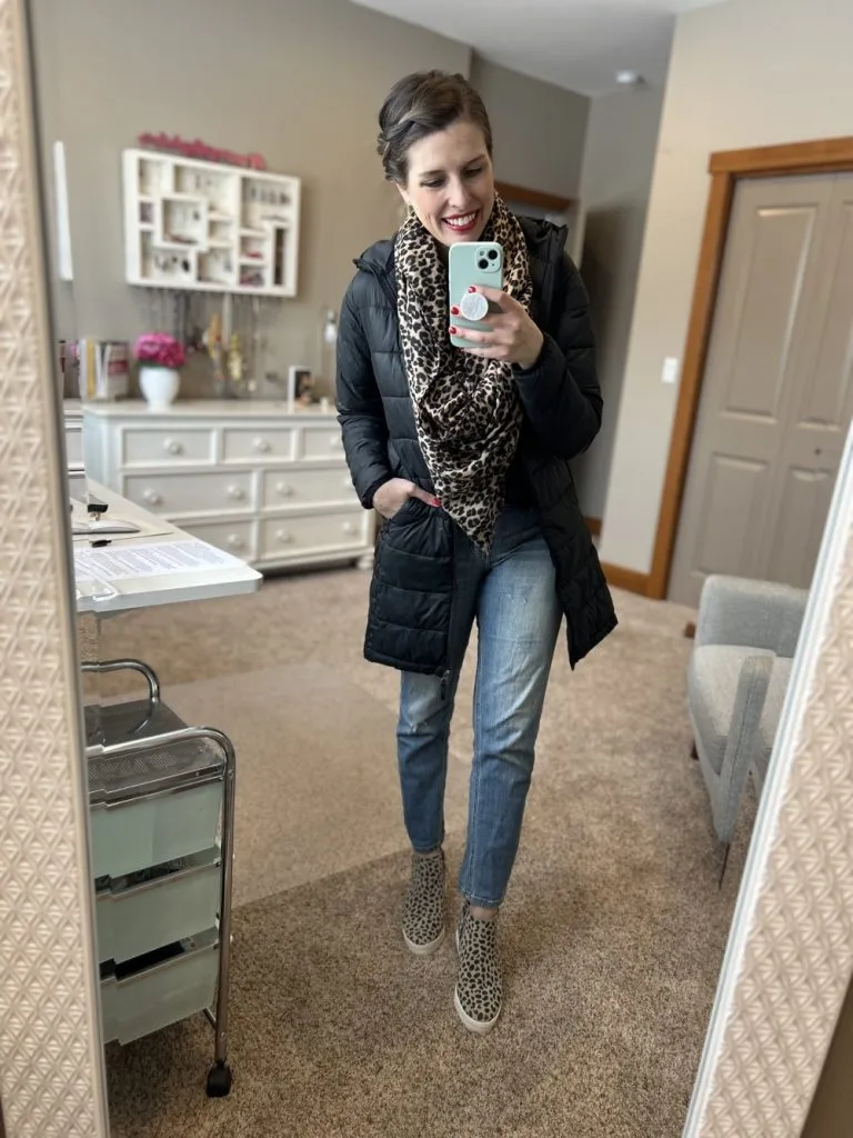 Woman wearing leopard scarf, puffer coat, and straight leg jeans for winter.