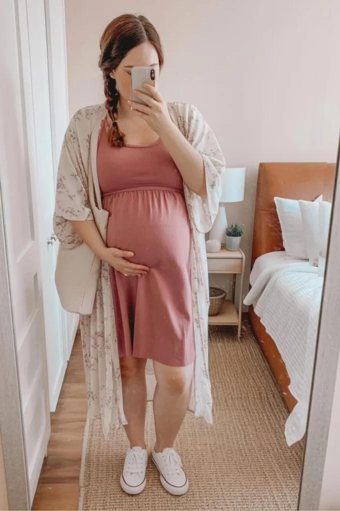 Midsize curvy pregnant woman in dusty rose tank dress and floral kimono taking mirror selfie—maternity teacher summer outfit.
