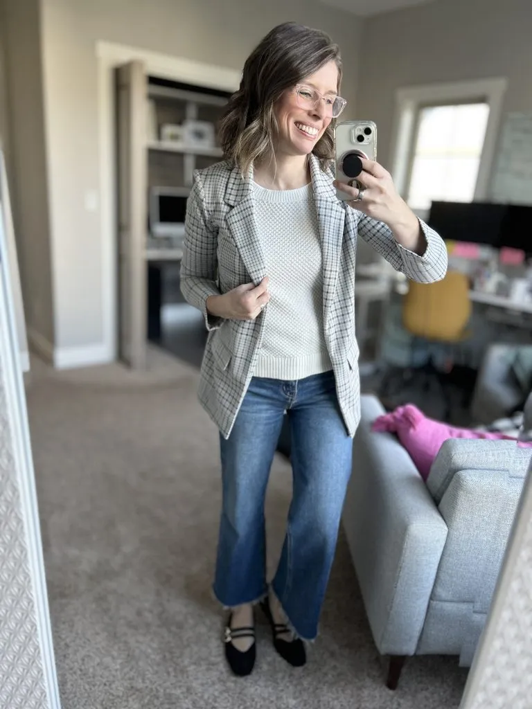 Woman wearing plaid blazer, cream sweater, and jeans, holiday work party outfit with jeans for women over 30