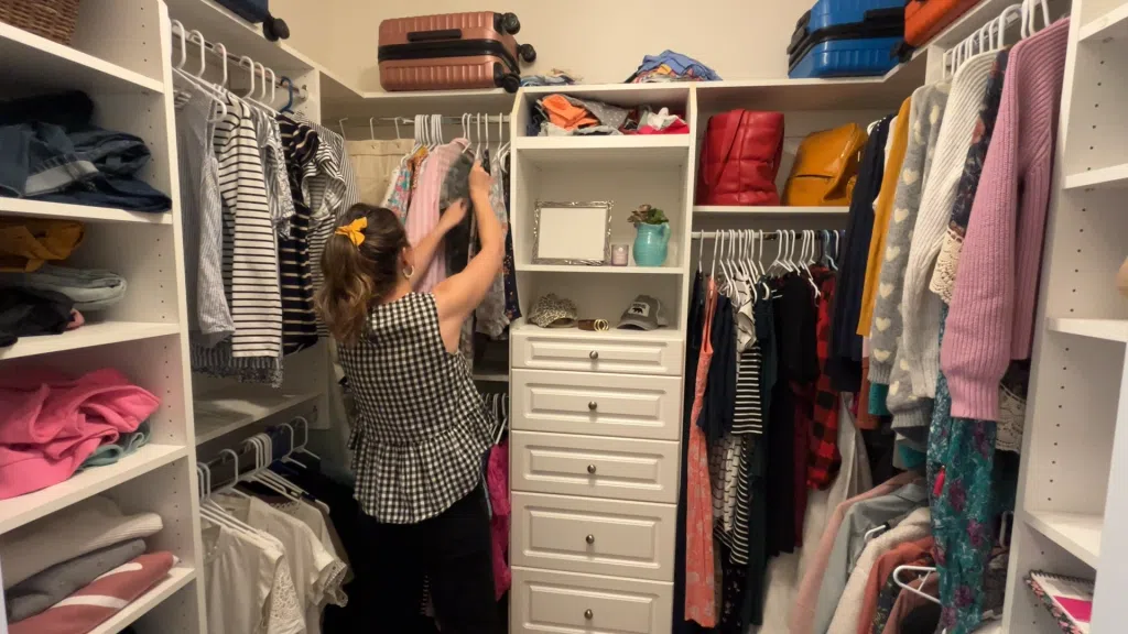 Woman decluttering closet, sorting clothes on hangers and removing extra items