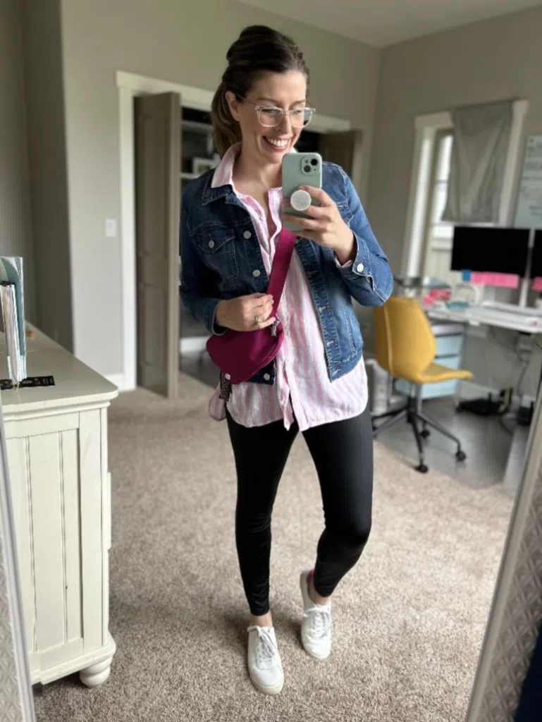 Woman wearing black leggings with a striped shirt and denim jacket in a mirror selfie