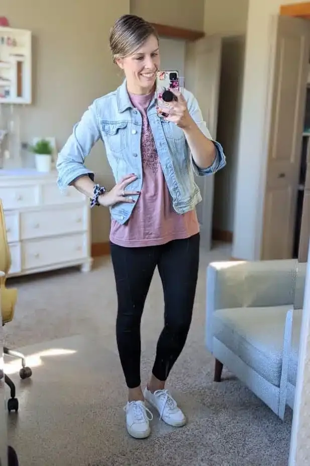 Woman wearing black leggings with a denim jacket and sneakers in a mirror selfie