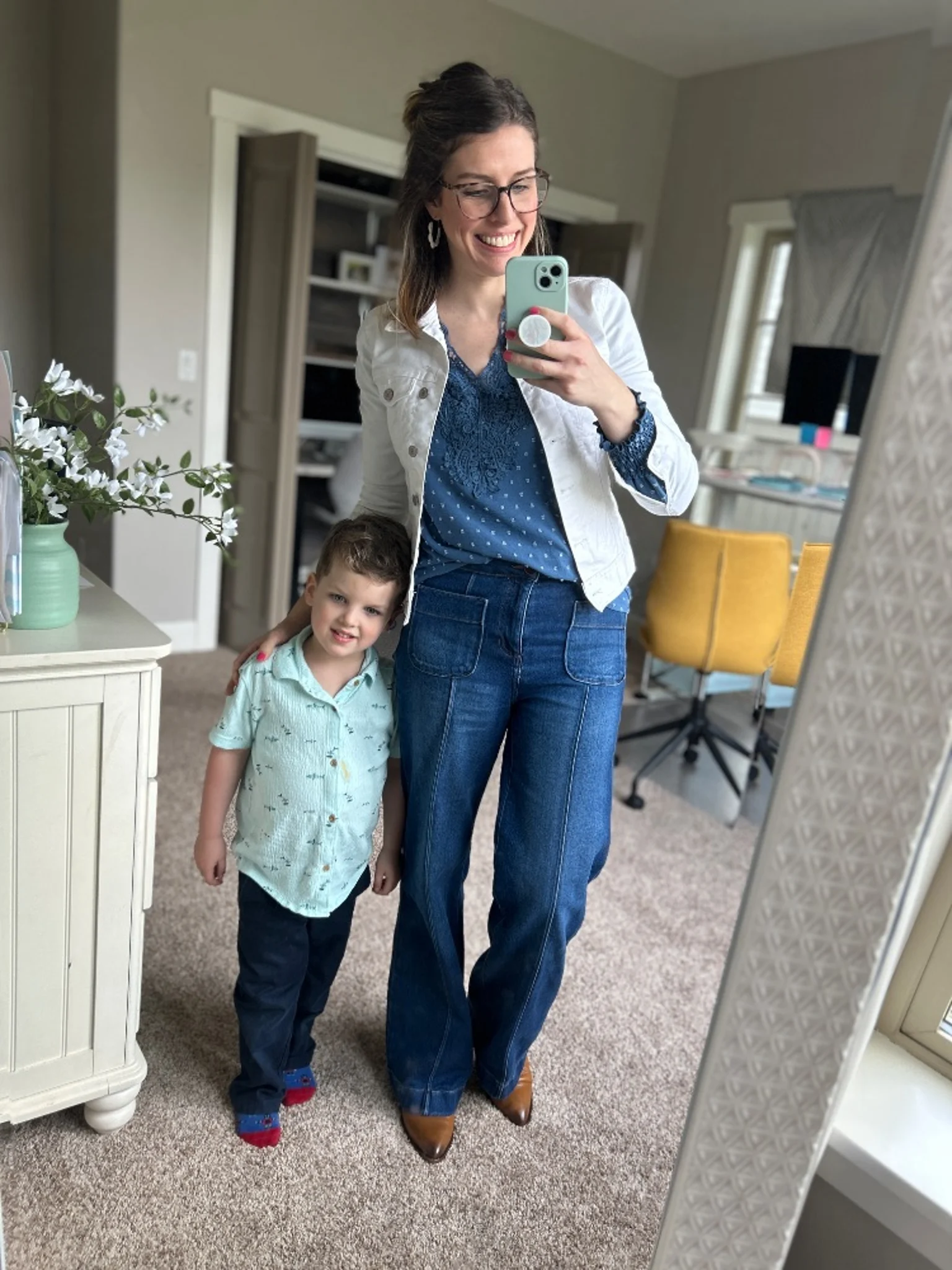 Mom wearing wide leg jeans with a blue top and denim jacket standing next to a child