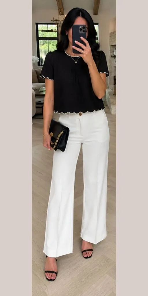 Woman wearing a black scallop hem tee with white wide leg trousers and black strappy heels for a chic summer date night outfit