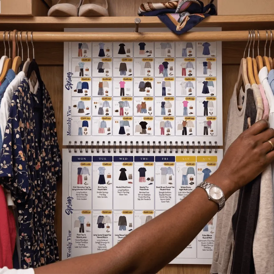 Arm reaching across an outfit calendar showing a monthly view of everyday outfits with outfit collages for women and teachers, perfect for fall outfits and quick mom looks.